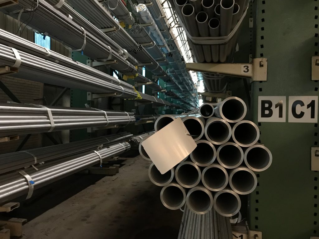 pexels-photo-15508178-15508178 Rows of steel tubes stacked in an industrial warehouse, showcasing organized storage.