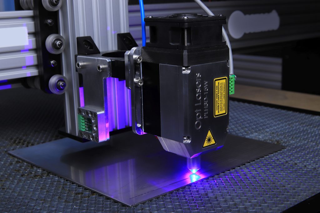 pexels-photo-7254419-7254419 Close-up of a laser engraving machine operating on a metal surface with blue laser light.